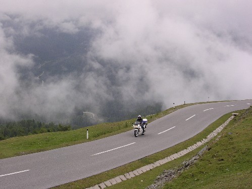 Serpentíny v strednej fáze stúpania na Eisental Höhe 2042m - pomedzi hmlu a lesy vidno priebeh Nockalmstrasse Serpentíny v strednej fáze stúpania na Eisental Höhe 2042m - pomedzi hmlu a lesy vidno priebeh Nockalmstrasse